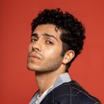 A photo of Mena Massoud, a Actor, who has a Dark Winter color profile.